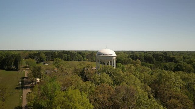 Aerial fly towards Corinthe Mississippi water tower in springtime with green trees