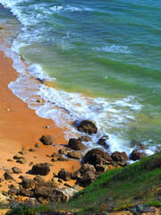 Sea surf at a typical Algarve beach with cliffs rocks and red sand