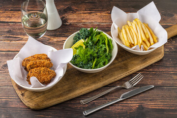 Crispy chicken wings with greens and french fries on wooden table