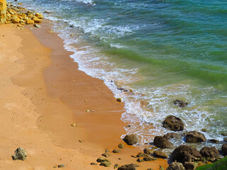 Sea surf at a typical Algarve beach with cliffs rocks and red sand