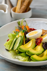 Healthy salad bowl with grilled chicken, avocado, egg, and blue cheese