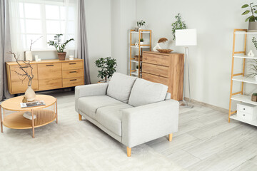 Interior of stylish modern living room with grey sofa, shelving unit and coffee table