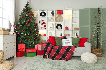 Interior of living room decorated for Christmas with sofa, shelving unit and dresser near window