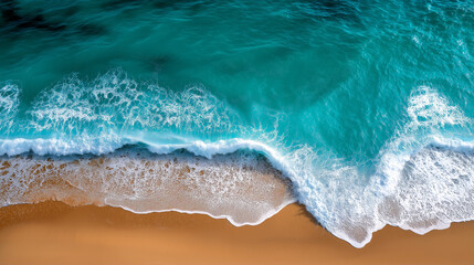 Aerial view of turquoise ocean waves gently crashing onto a golden sandy beach.
