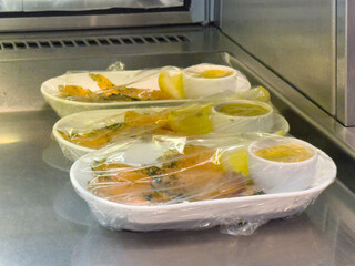 Airplane meals: wrapped trays with shrimp, lemon and sauce cups in airplane galley