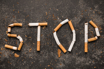 Word STOP made of cigarette butts on dark background. No Tobacco Day concept