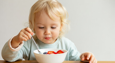 Caucasian young child enjoying healthy fruit breakfast with strawberries and blueberries
