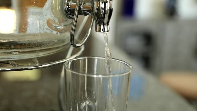 A dispenser fills a glass of water.