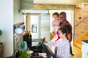 Father cooking breakfast with daughters in cozy kitchen on a sunny morning