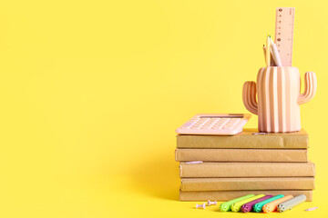 Different school stationery with books on yellow background