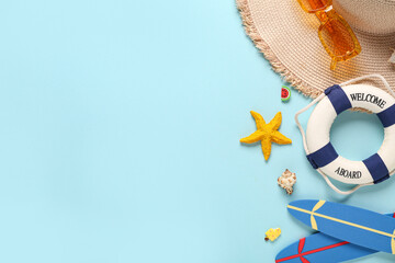 Hat with sunglasses, lifebuoy and different beach decor on blue background