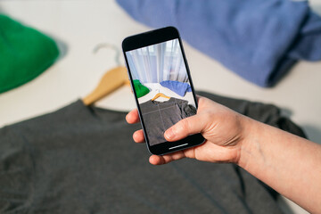 Woman taking photo of used clothes in good quality. Preparing to sell in second hand online market. Second hand and resale concept. Clothes donation.