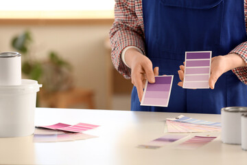 Young woman with violet paint palette swatches near table at home, closeup