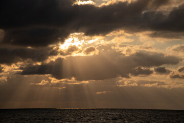 Beautiful sunset over the ocean with rays of light breaking through clouds