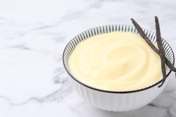 Tasty vanilla pudding and pods on white marble table, closeup. Space for text