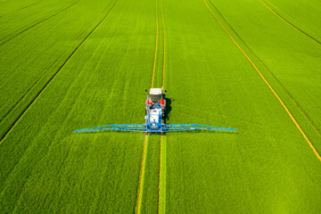 Pesticide aplication. A tractor with chemical sprayer working on a field.