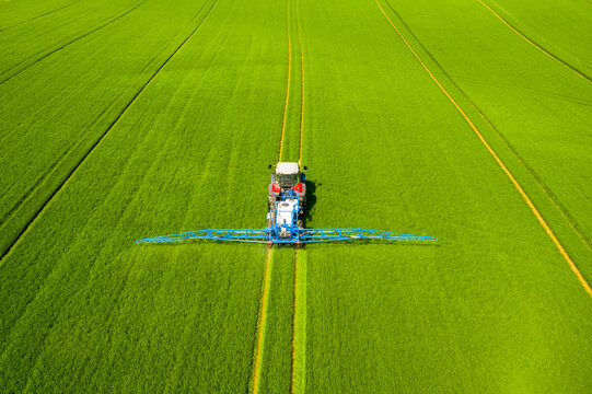 Pesticide aplication. A tractor with chemical sprayer working on a field.