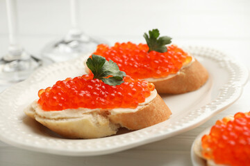 Tasty sandwiches with red caviar on white wooden table, closeup