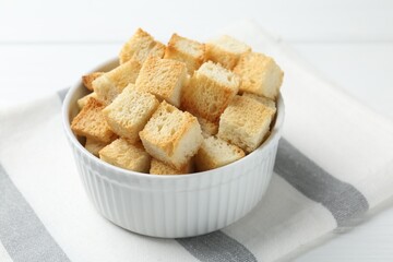 Delicious crispy croutons on white table, closeup