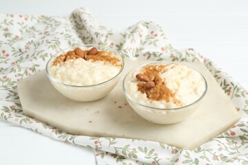 Delicious rice pudding with cinnamon and almonds in glass bowls on white table