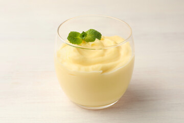 Tasty vanilla pudding with mint on white wooden table, closeup