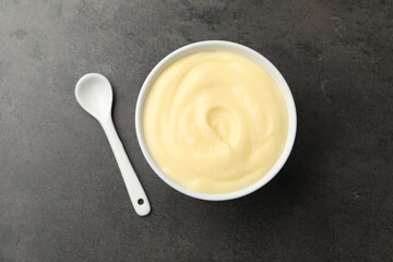 Tasty vanilla pudding with spoon on black table, top view