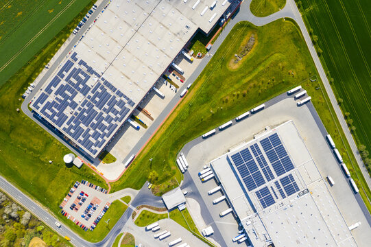 Industry with low carbon footprint. Industrial warehouses with solar panels on the roof. Technology park and factories from above