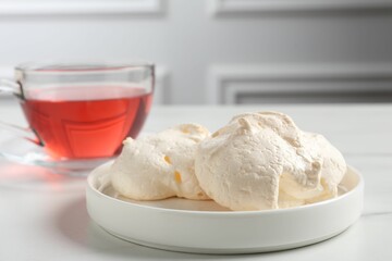 Delicious homemade meringue cookies and tea on light table, closeup