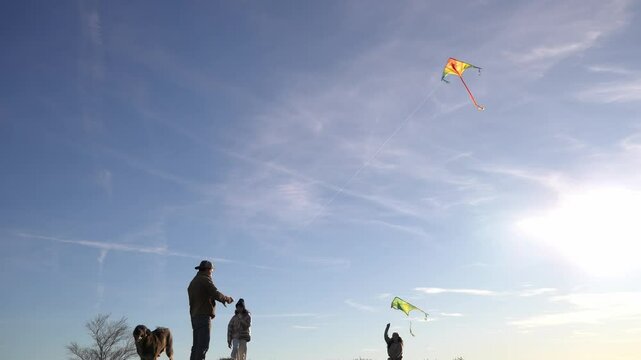 Father and daughters flying kites on a sunny day