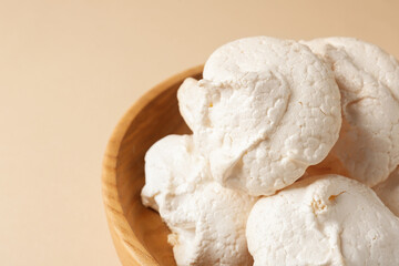 Delicious homemade meringue cookies in bowl on beige background, closeup