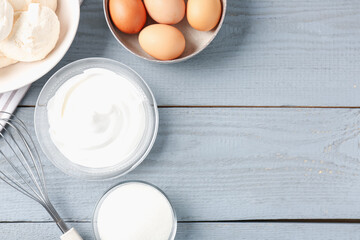 Delicious homemade meringue cookies, ingredients and whisk on gray wooden table, flat lay. Space...