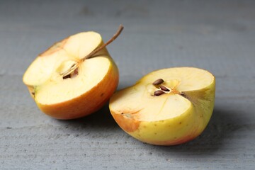 Halves of overripe apple on grey wooden table, closeup