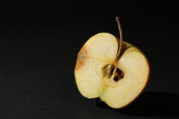 Half of overripe apple on black background, closeup. Space for text