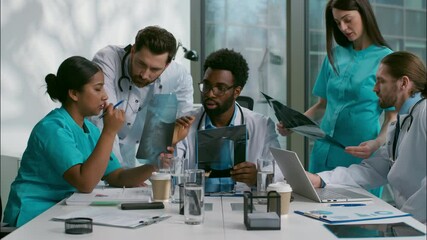 Multiethnic group doctors nurse meeting medical team talking together discuss x-ray patient results consulting each other surgery brainstorming health discussion healthcare in conference room hospital - Powered by Adobe