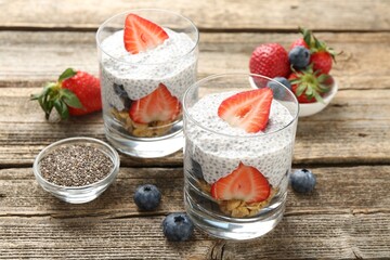 Delicious dessert with chia seeds, yogurt, granola, strawberries and blueberries on wooden table, closeup. Superfood