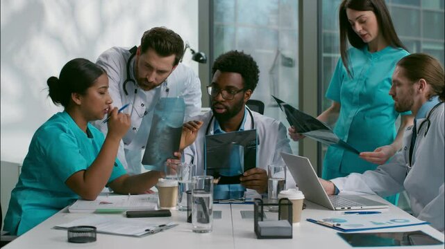 Multiethnic group doctors nurse meeting medical team talking together discuss x-ray patient results consulting each other surgery brainstorming health discussion healthcare in conference room hospital