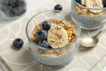 Delicious dessert with chia seeds, yogurt, granola, blueberries and banana on table, closeup. Superfood