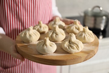Woman with many uncooked khinkali in kitchen, closeup