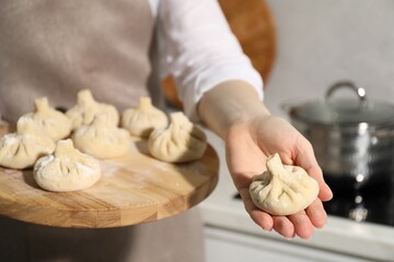 Woman with many uncooked khinkali in kitchen, closeup