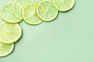 Slices of fresh limes on pale green background, flat lay. Space for text