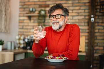 senior mature man enjoy at home while eat salad and drink water