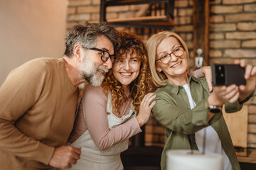 Smiling mum, dad and daughter posing for self portrait on cell