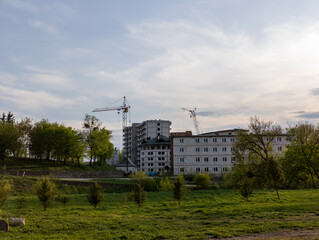 Fototapeta premium A large building with cranes in the background in a grassy field