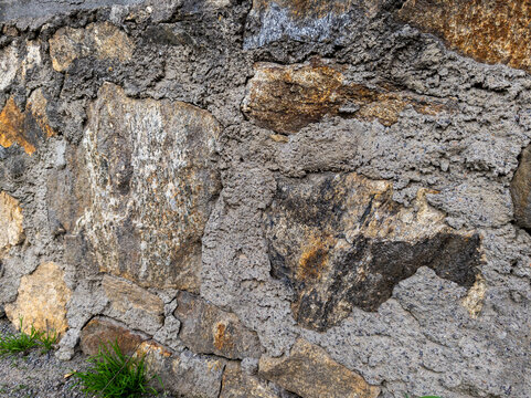 A stone wall with moss growing out of it