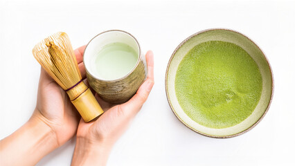 Aromatic matcha tea is being prepared in a ceramic bowl, featuring a traditional whisk and cup