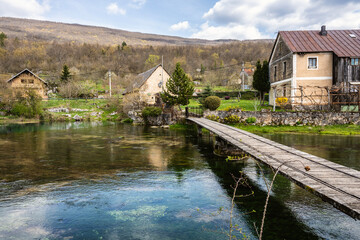 Old, beautiful stone houses and old, wooden footbridge of Majerovo Vrilo, located in the village of Sinac, Croatia, next to the Gacka river spring.