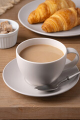 Freshly baked croissants served with a hot cup of coffee on a wooden table in a cozy setting