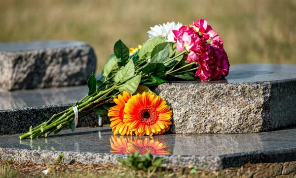 Colorful flowers placed on gravestone in cemetery