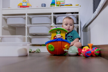 A baby sits on the floor, happily playing with toys