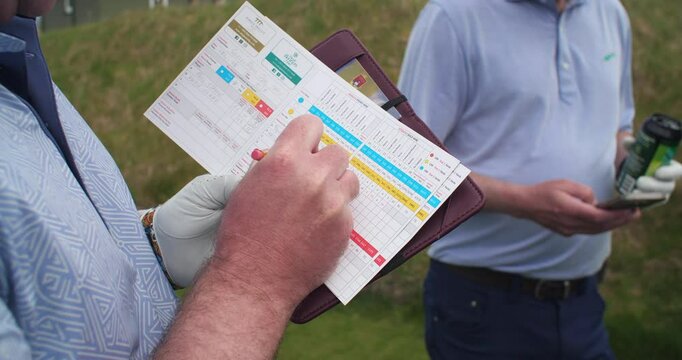 Golfers write score in score card round of golf